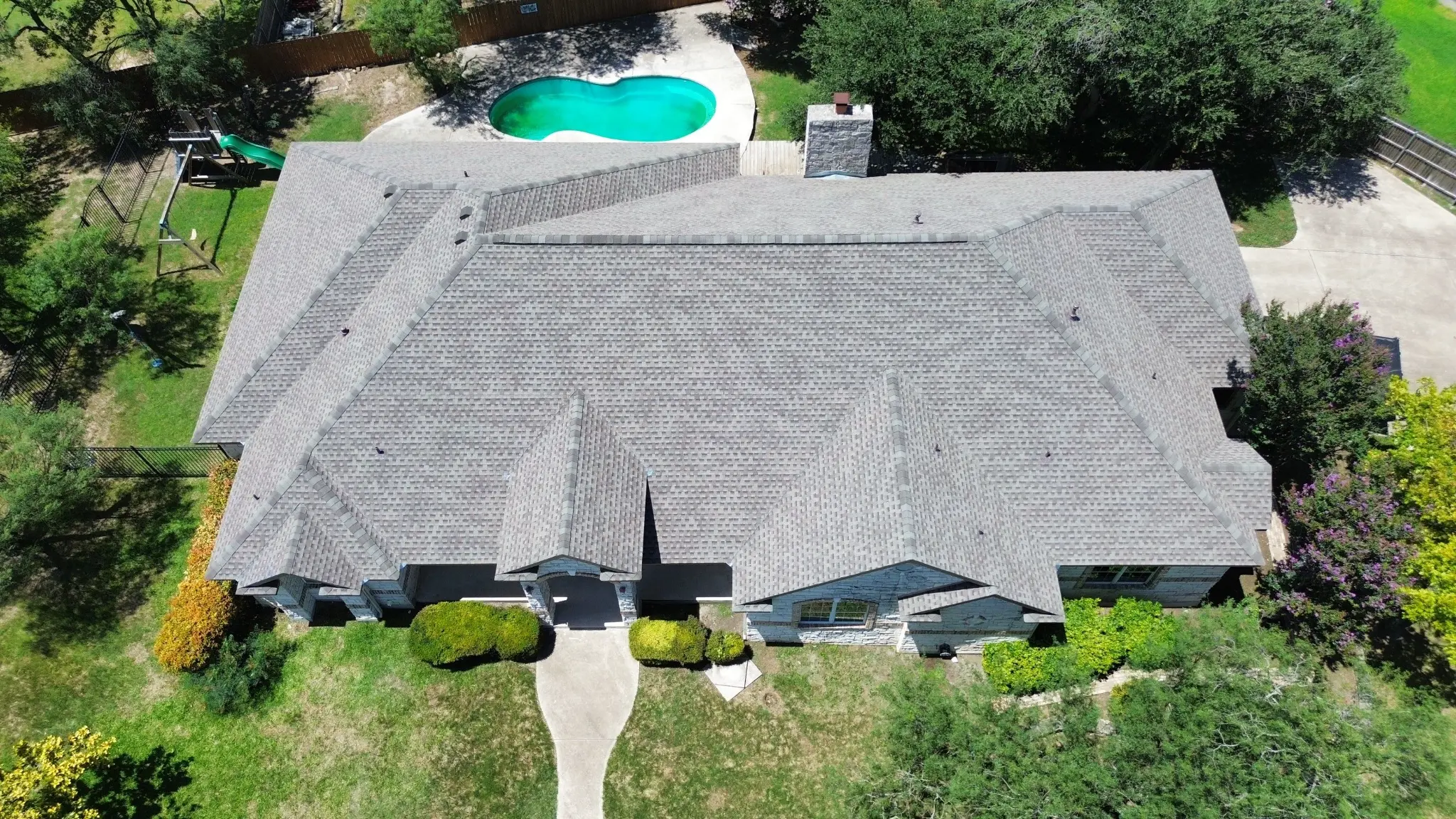 Completed gray architectural shingle roof installation by Roof Royale on a Texas stone home