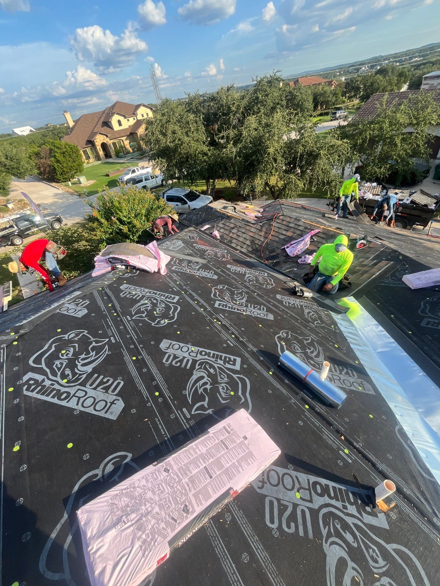Roofing crew installing RhinoRoof underlayment during a Texas roof replacement